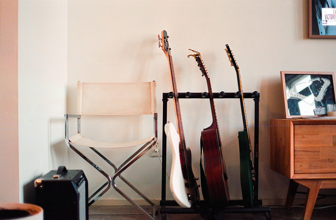 A director’s chair, practice amplifier, and three guitars in a quiet corner.